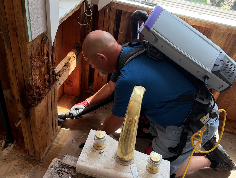 Technician extracting water from a flooded floor during emergency mitigation